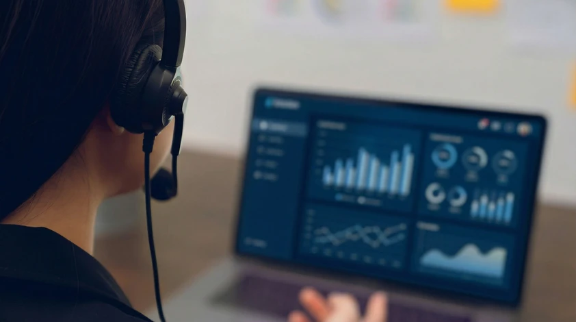 Scène de bureau moderne avec deux professionnels collaborant devant un écran d'ordinateur, analysant des données et graphiques